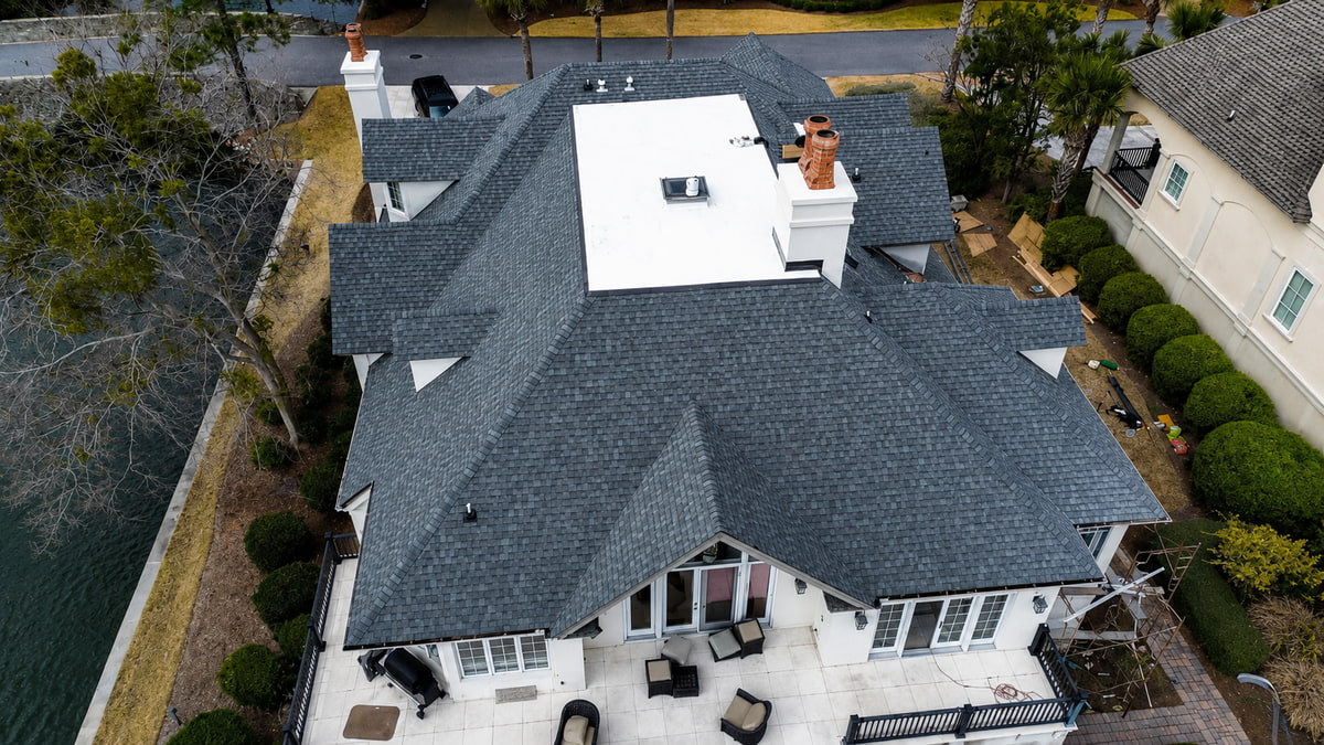 Aerial view of a completed JJ Roofing project: architectural shingle and low-slope TPO roof on a Lowcountry home