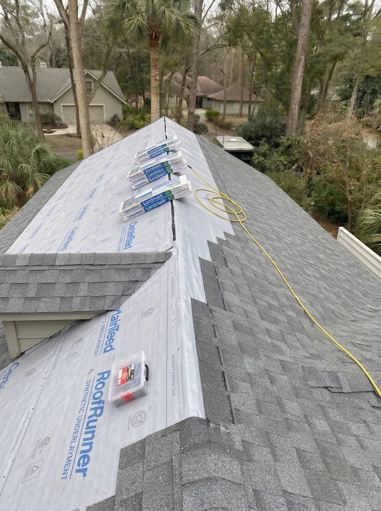 Roof mid-tear-off: synthetic underlayment laid down, CertainTeed Landmark shingle bundles staged on the ridge