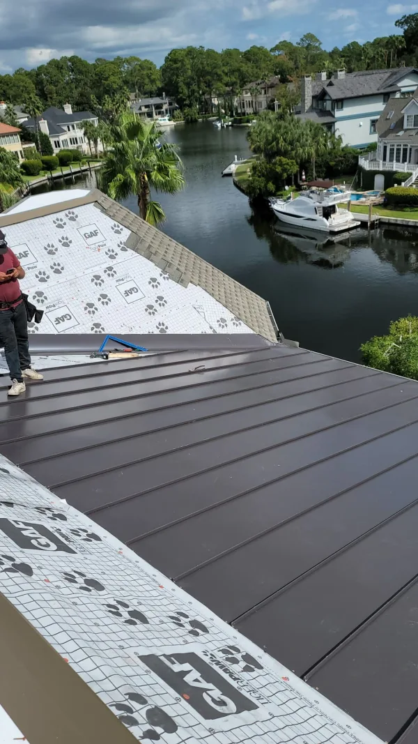 Aerial view of a standing-seam metal roof on a Lowcountry plantation home, marsh and palms behind